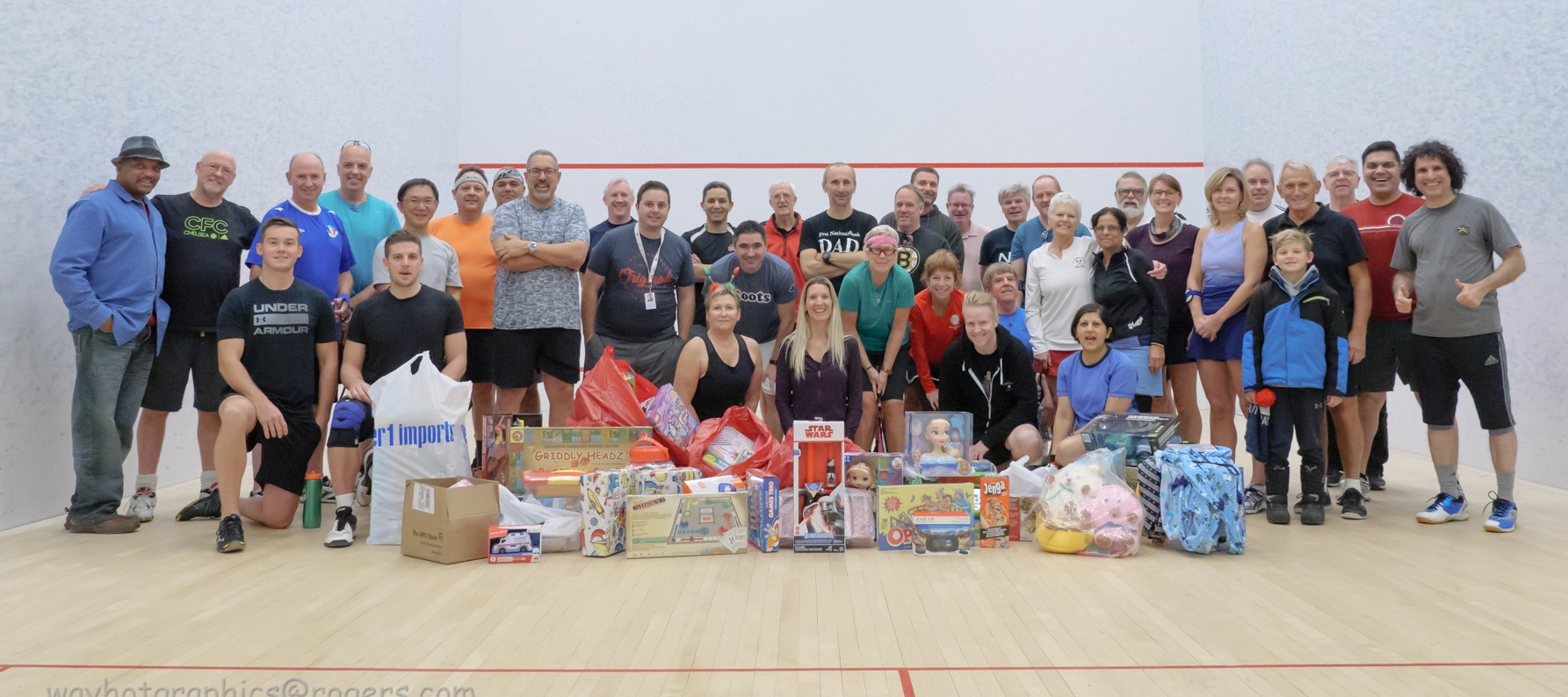 Large group of Pickering Squash Club members posing with collected toys during the annual Holiday Toy Drive event.